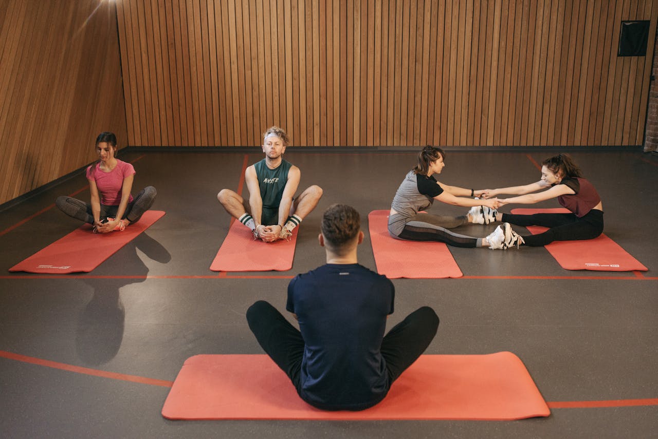 home-img People engaging in a yoga class with red mats in an indoor wooden studio.